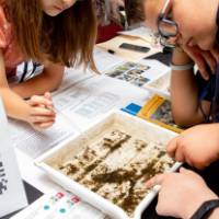 two student examine a tray of macroinvertebrates at student project showcase